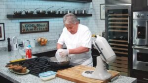 A Chef in A White Uniform Adding Ingredients to Freshly Made Butter in A Stainless Steel Bowl in A Professional Kitchen
