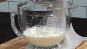 A Stand Mixer with A Glass Bowl Whipping Heavy Cream, Beginning the Process of Making Butter